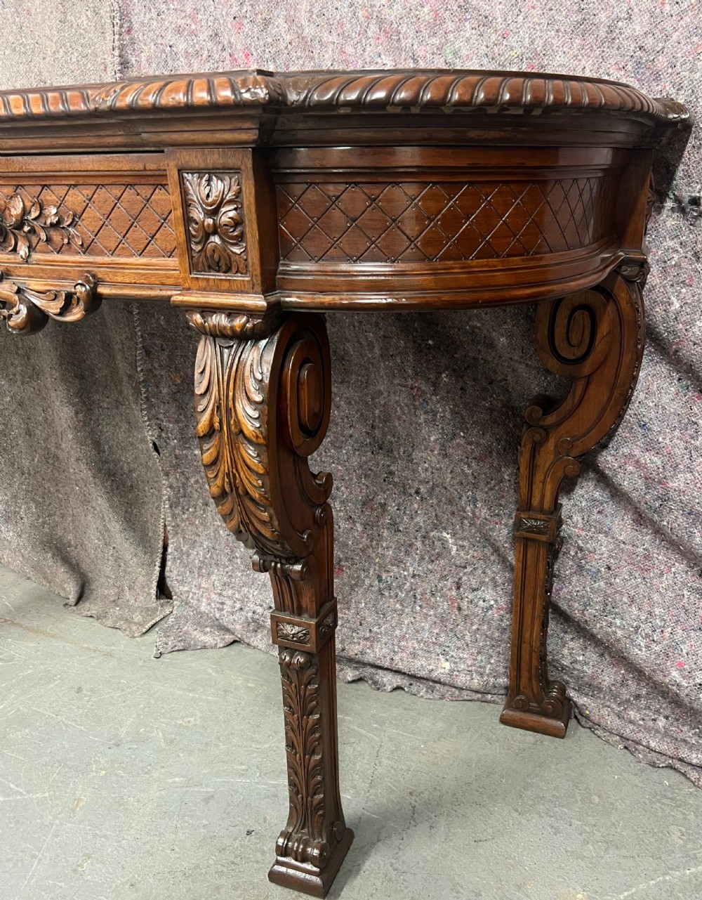 An antique dark brown carved wood console table featuring a shell motif central frieze and detailed scrolled legs. View VII