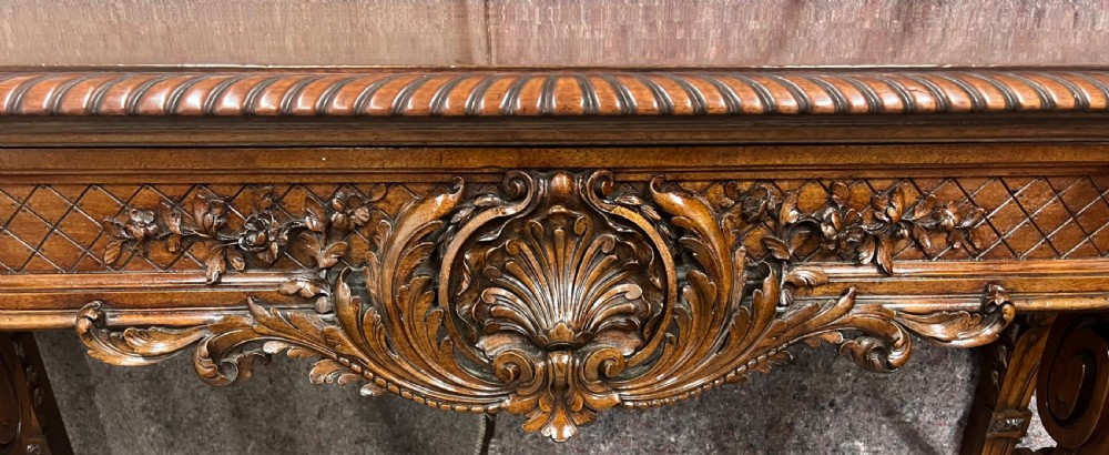An antique dark brown carved wood console table featuring a shell motif central frieze and detailed scrolled legs. View XI