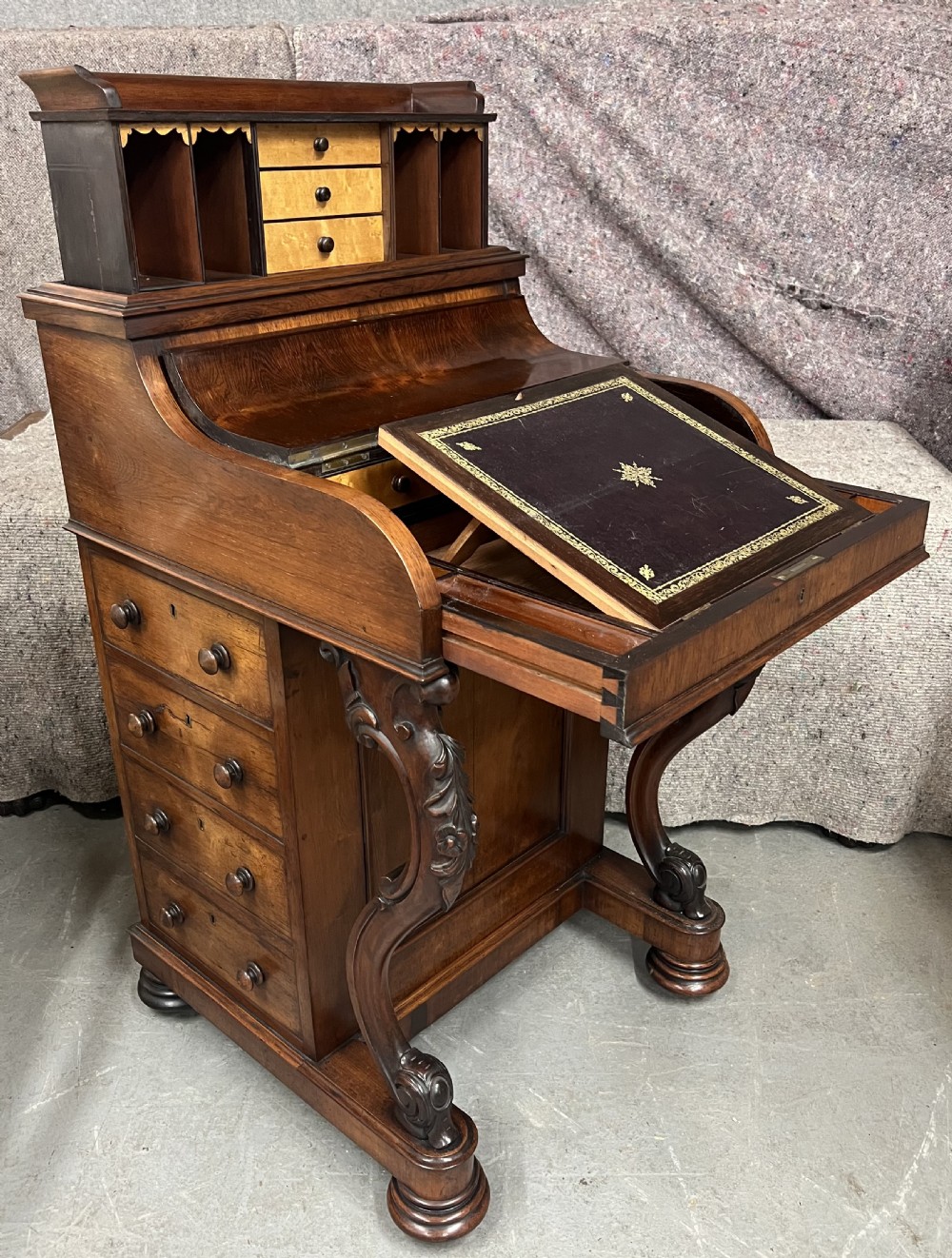 A Victorian rosewood Davenport writing desk featuring a pop-up stationery compartment, sloped leather writing surface, and carved cabriole legs.