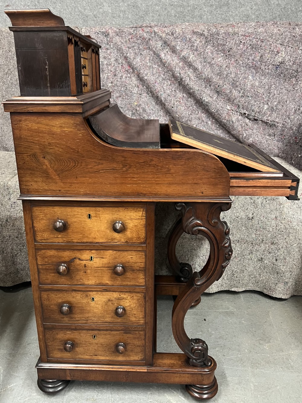 A Victorian rosewood Davenport writing desk featuring a pop-up stationery compartment, sloped leather writing surface, and carved cabriole legs. View VI