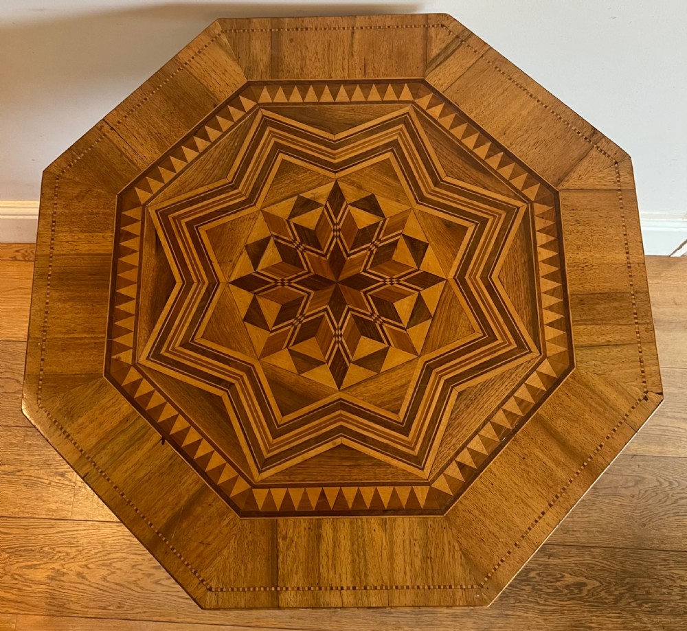 An octagonal wooden occasional table featuring geometric marquetry star patterns on the top and a turned pedestal column supported by three inlaid legs. View II