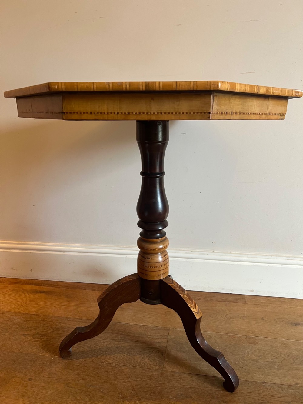 An octagonal wooden occasional table featuring geometric marquetry star patterns on the top and a turned pedestal column supported by three inlaid legs. View VI