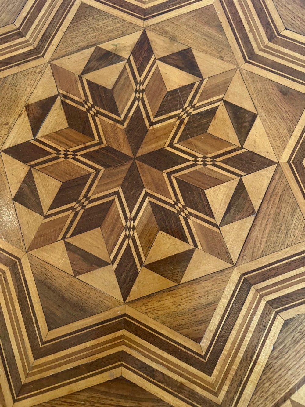 An octagonal wooden occasional table featuring geometric marquetry star patterns on the top and a turned pedestal column supported by three inlaid legs. View VIII