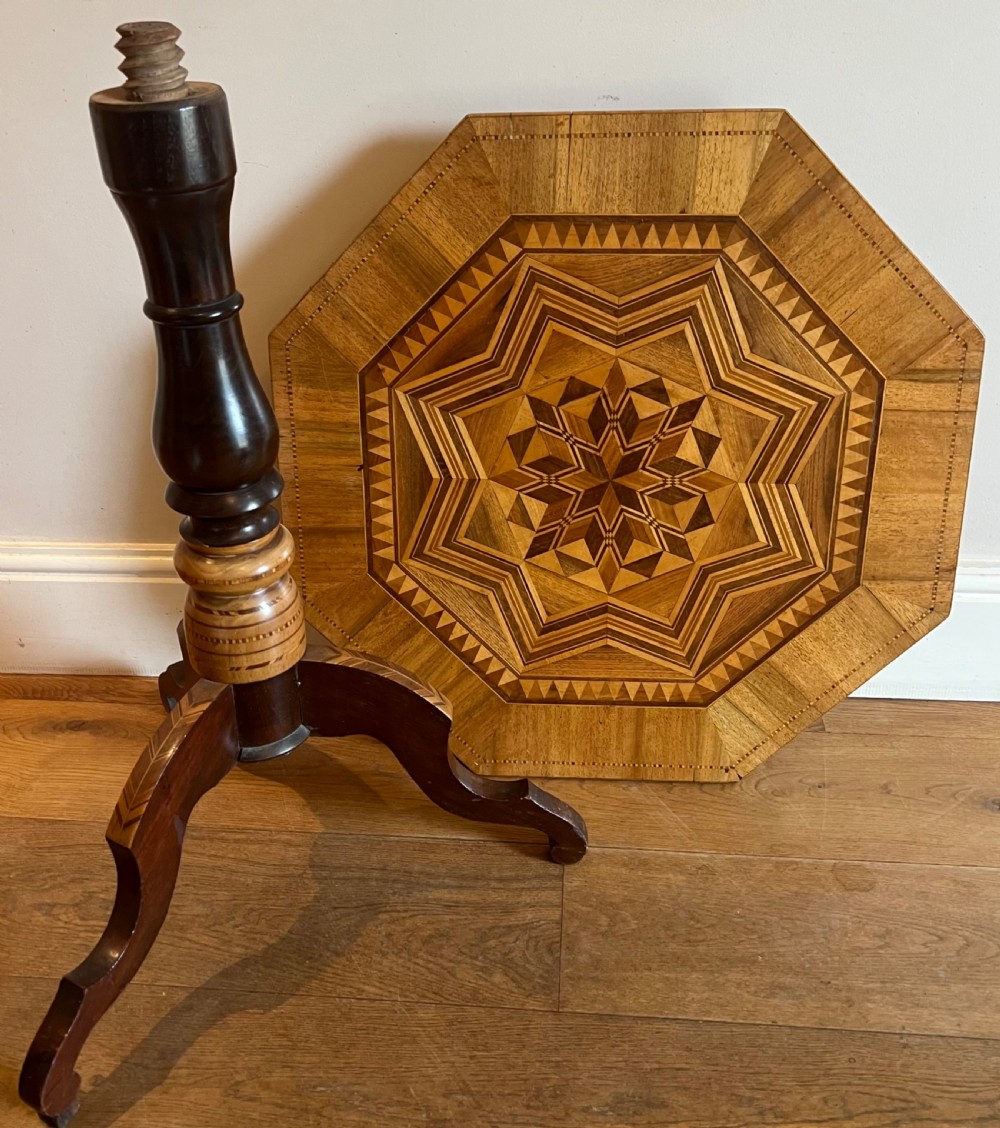 An octagonal wooden occasional table featuring geometric marquetry star patterns on the top and a turned pedestal column supported by three inlaid legs. View IX