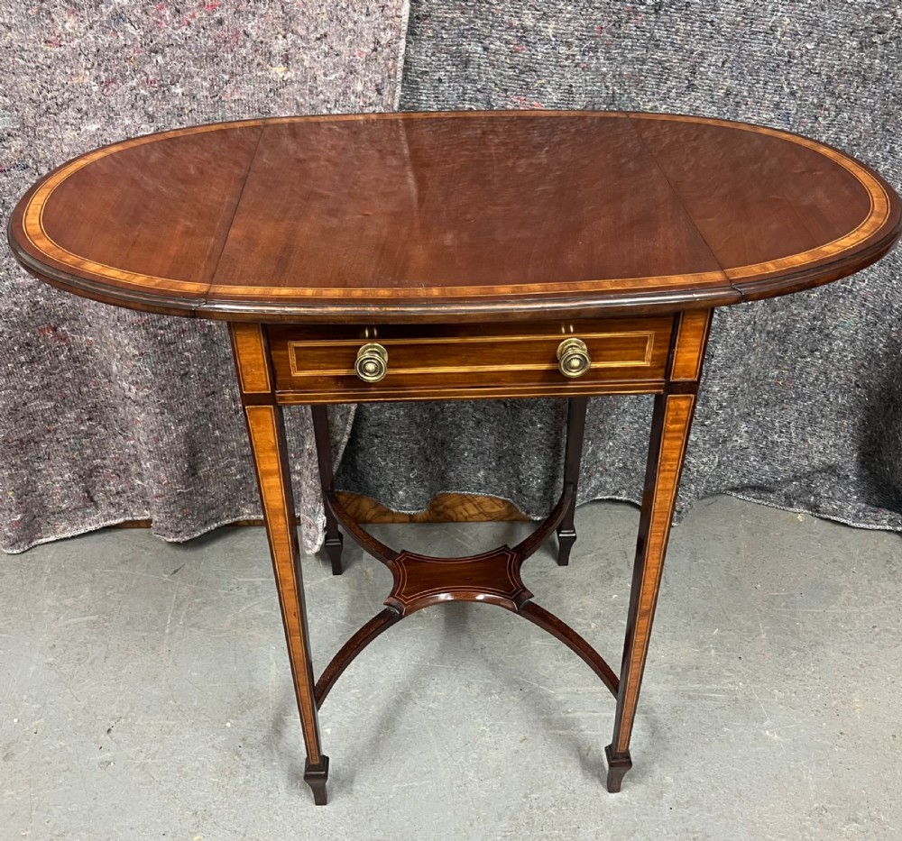 An Edwardian mahogany Pembroke side table featuring satinwood crossbanding, drop leaves, a single drawer with twin brass handles, square tapered legs, and a curved lower X-stretcher. View II