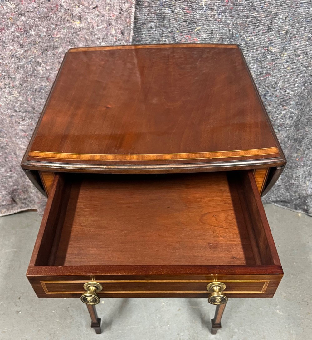 An Edwardian mahogany Pembroke side table featuring satinwood crossbanding, drop leaves, a single drawer with twin brass handles, square tapered legs, and a curved lower X-stretcher. View VIII