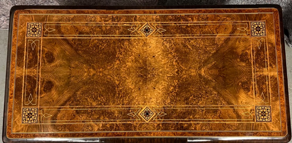 A Victorian burr walnut card table featuring geometric Tunbridge Ware inlay, turned twin-column supports, and a stretcher base on castors. View II