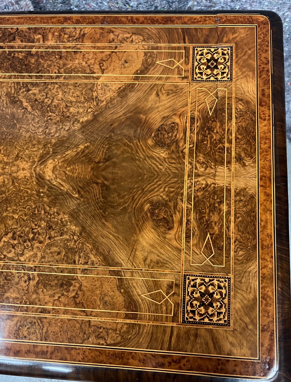 A Victorian burr walnut card table featuring geometric Tunbridge Ware inlay, turned twin-column supports, and a stretcher base on castors. View III