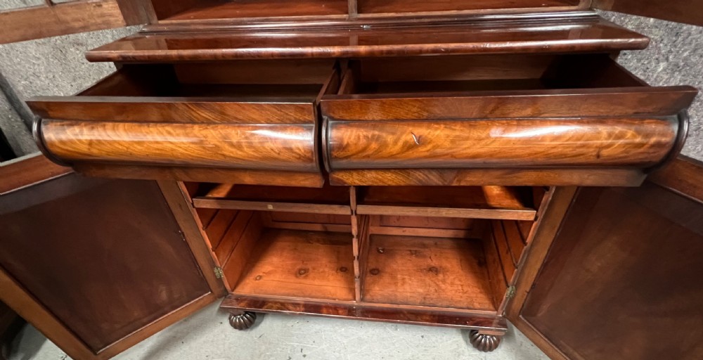 An antique flame mahogany chiffonier bookcase featuring a glazed two-door top cabinet above a lower base with two arched panelled cupboard doors. View III