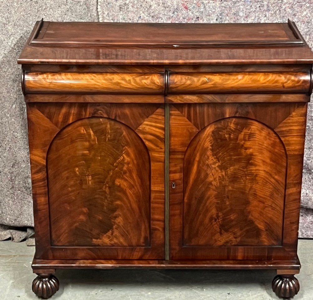 An antique flame mahogany chiffonier bookcase featuring a glazed two-door top cabinet above a lower base with two arched panelled cupboard doors. View V