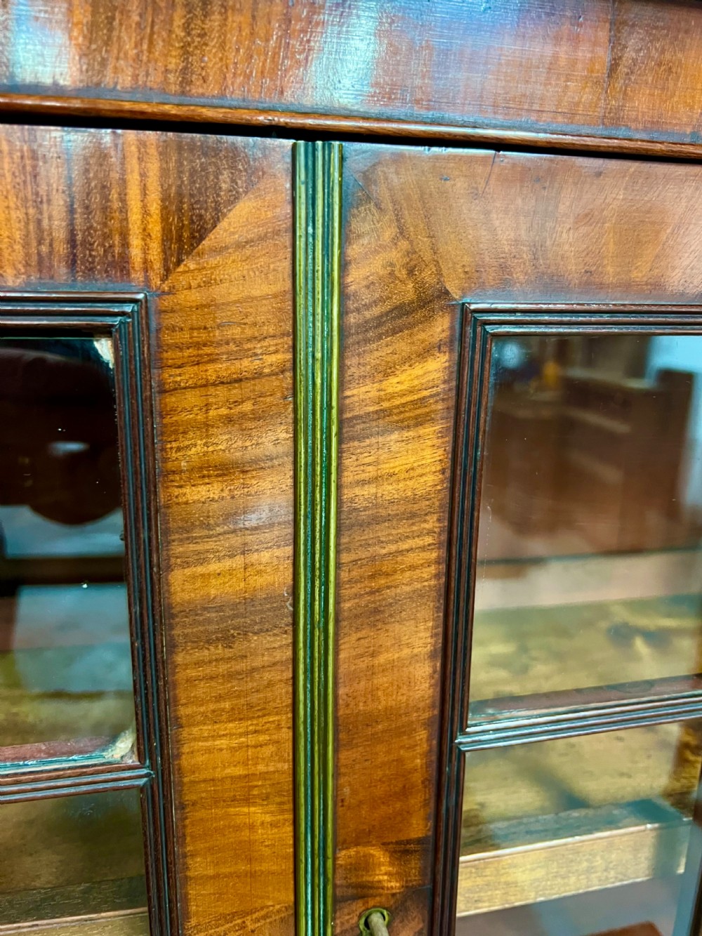 An antique flame mahogany chiffonier bookcase featuring a glazed two-door top cabinet above a lower base with two arched panelled cupboard doors. View XII