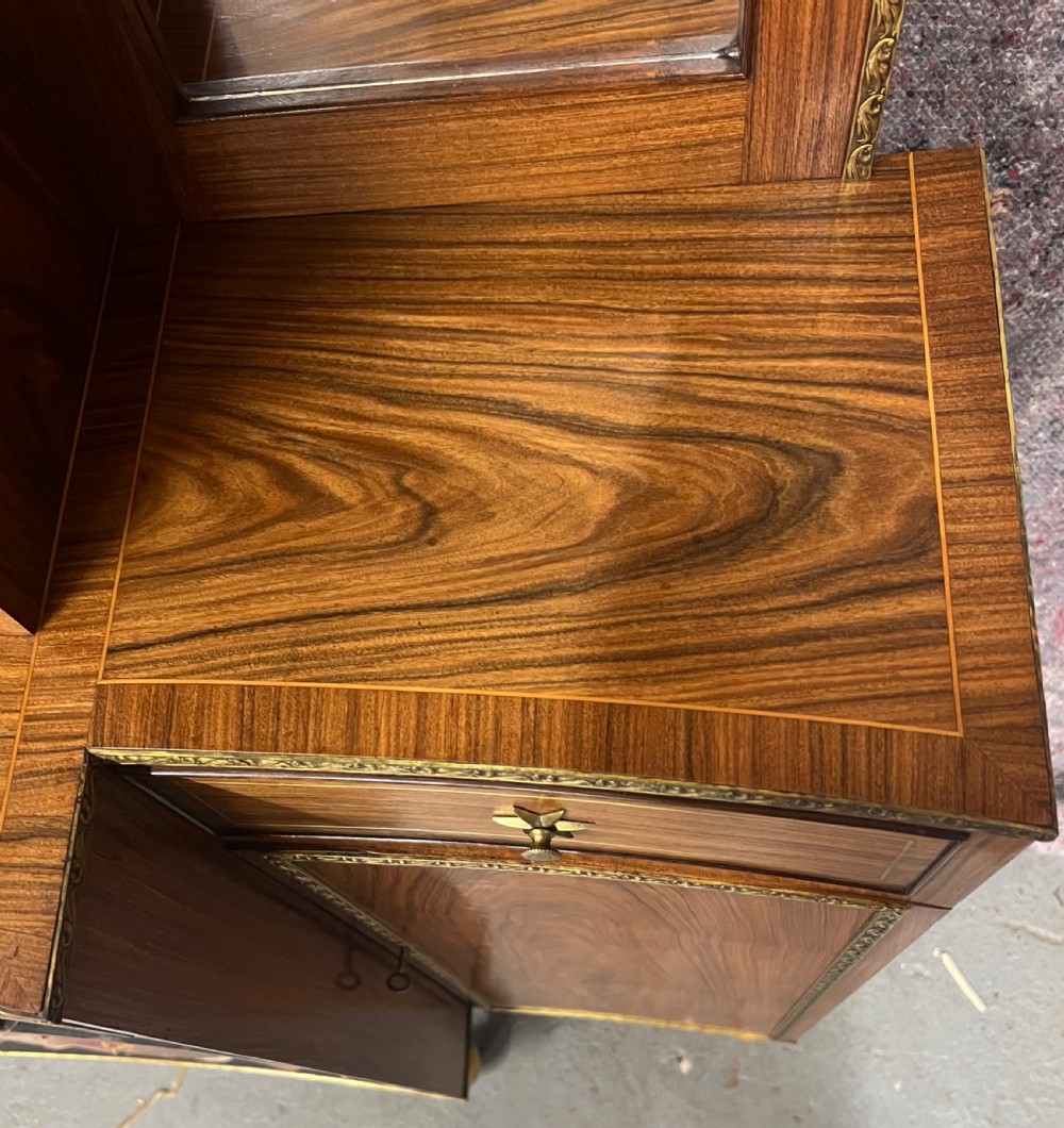 A Regency style rosewood breakfront open bookcase with tiered shelving filled with books, brass star handles, mirrored side compartments, and turned legs. View XIII