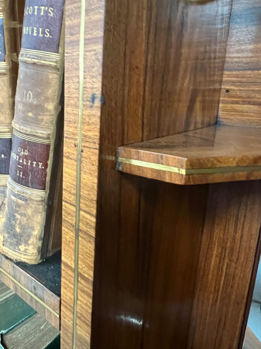 A Regency style rosewood breakfront open bookcase with tiered shelving filled with books, brass star handles, mirrored side compartments, and turned legs. View XIV