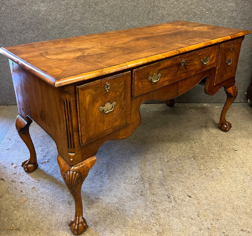 An antique walnut writing desk featuring three drawers, crossbanded veneer top, carved cabriole legs, and claw and ball feet. View XV