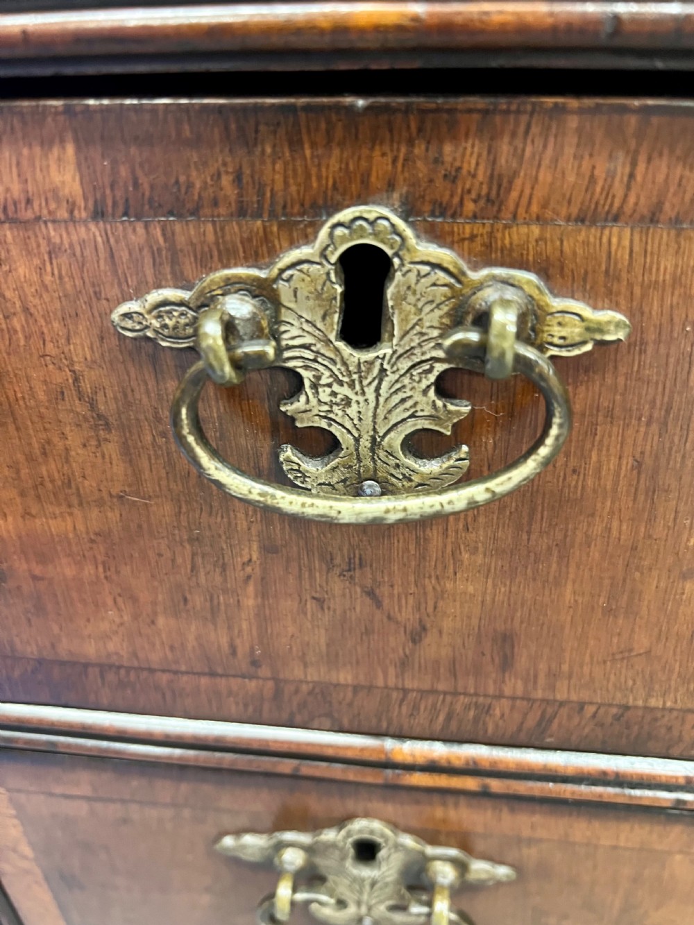 An 18th-century style walnut kneehole desk featuring a top drawer, six pedestal drawers with brass drop handles, a central recessed cupboard, and bracket feet. View V