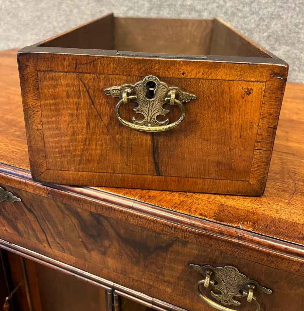 An 18th-century style walnut kneehole desk featuring a top drawer, six pedestal drawers with brass drop handles, a central recessed cupboard, and bracket feet. View VI