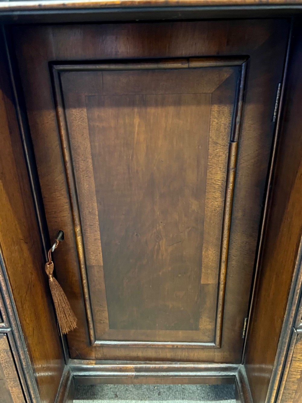 An 18th-century style walnut kneehole desk featuring a top drawer, six pedestal drawers with brass drop handles, a central recessed cupboard, and bracket feet. View VII