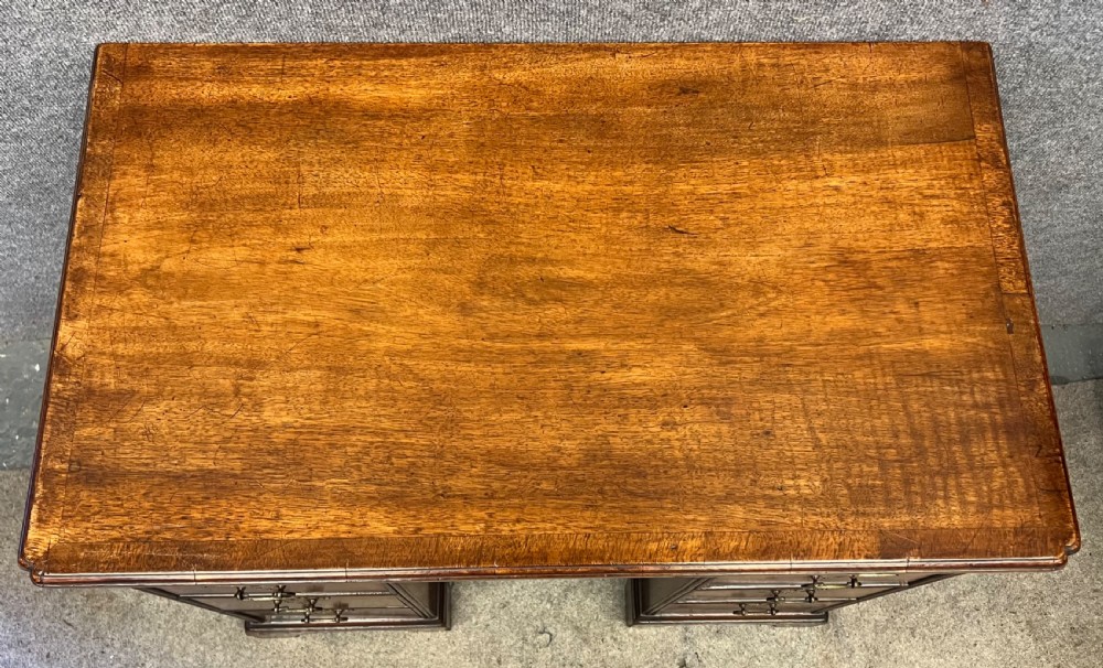 An 18th-century style walnut kneehole desk featuring a top drawer, six pedestal drawers with brass drop handles, a central recessed cupboard, and bracket feet. View XI