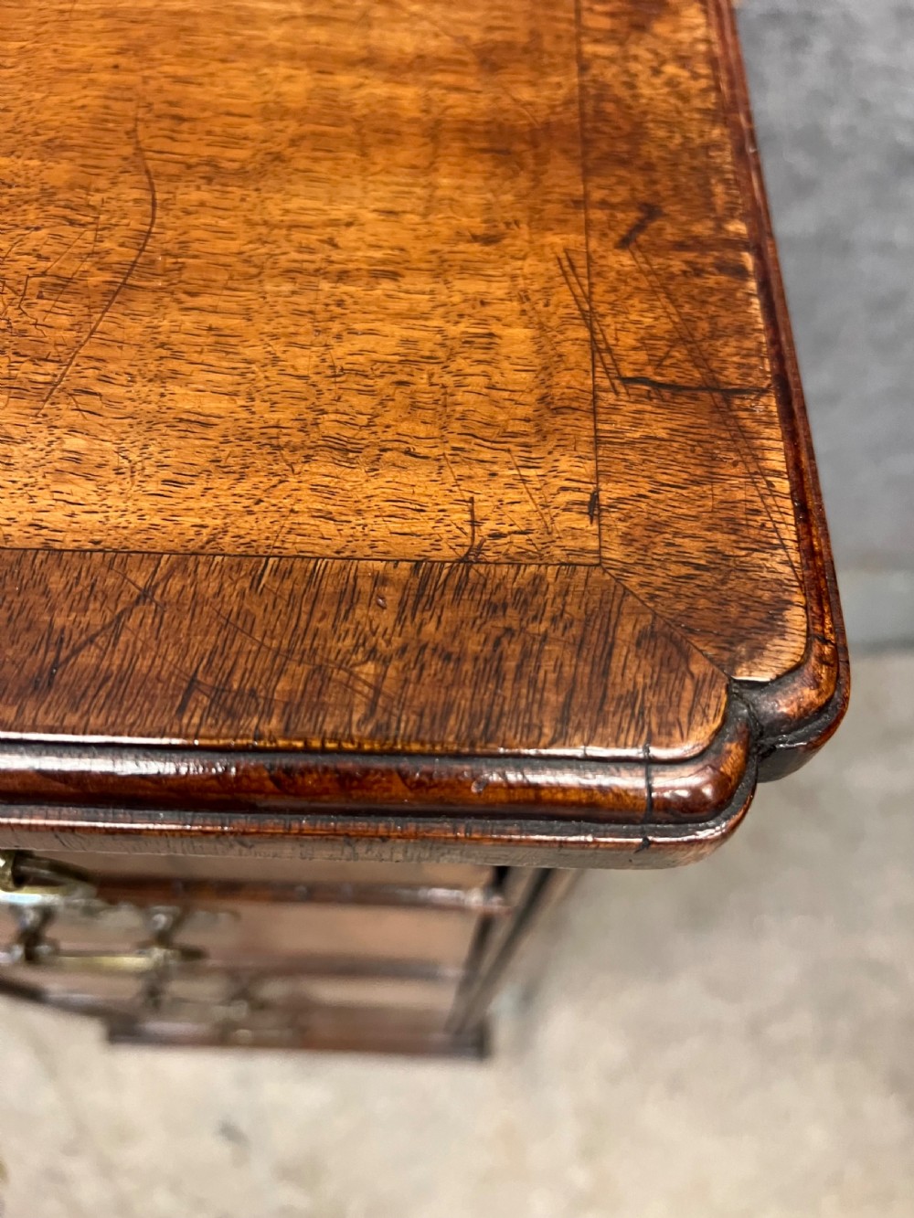 An 18th-century style walnut kneehole desk featuring a top drawer, six pedestal drawers with brass drop handles, a central recessed cupboard, and bracket feet. View XII