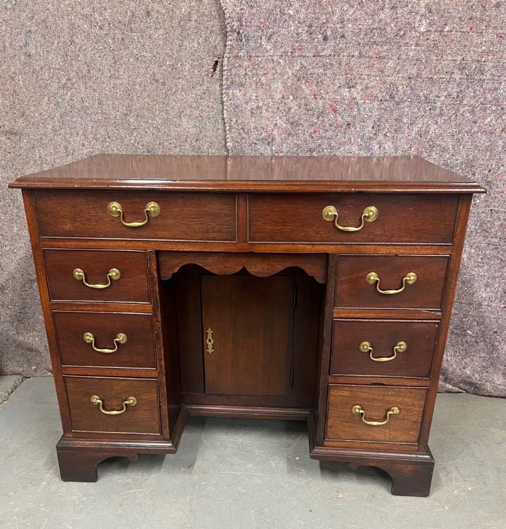 A George III mahogany kneehole desk featuring multiple drawers with brass swan-neck handles, a central recessed cupboard, and bracket feet. View II