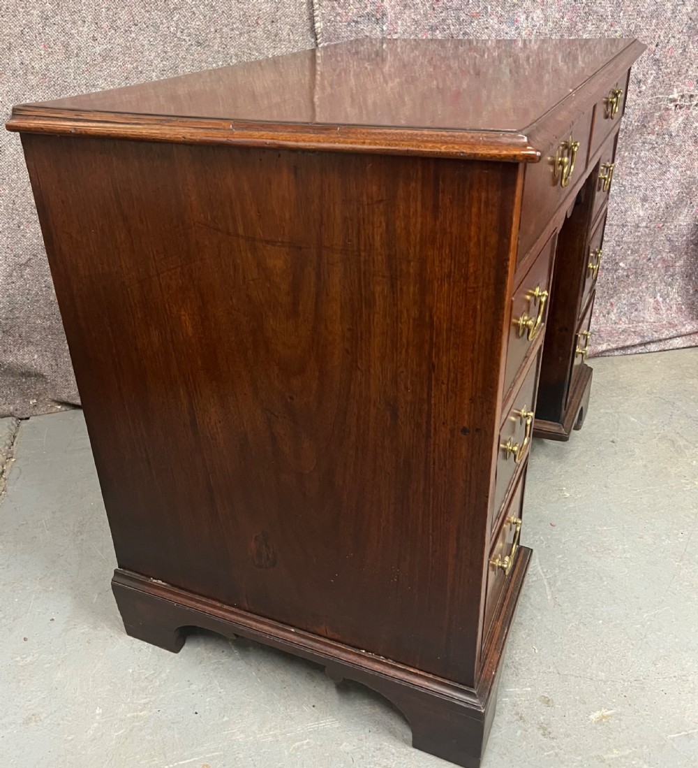 A George III mahogany kneehole desk featuring multiple drawers with brass swan-neck handles, a central recessed cupboard, and bracket feet. View III