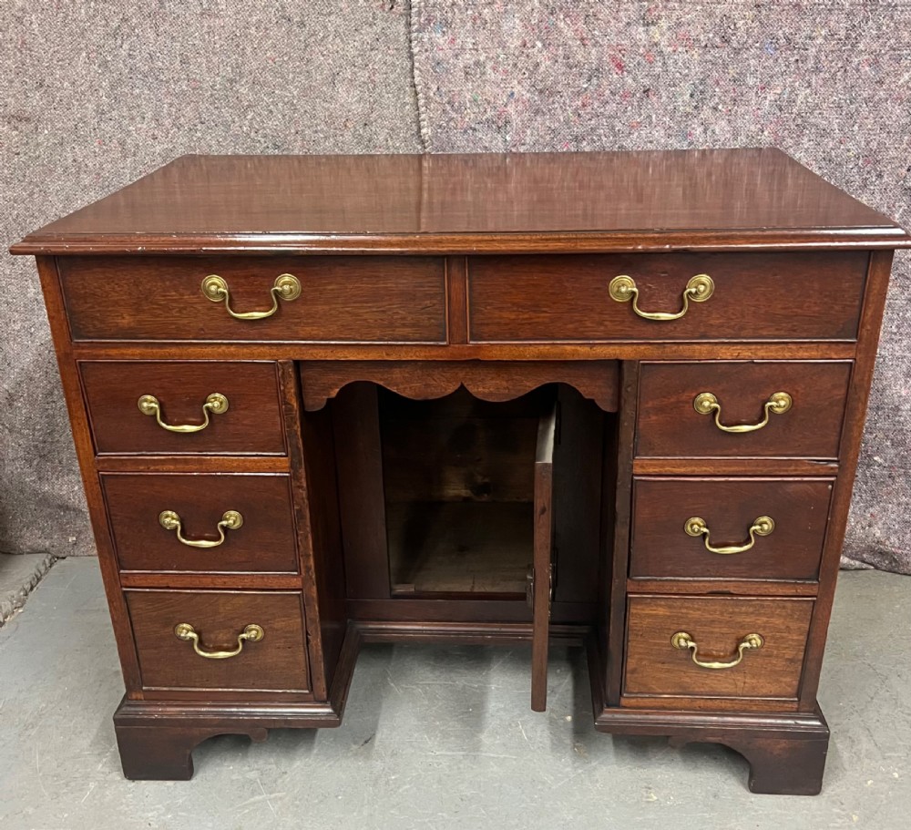 A George III mahogany kneehole desk featuring multiple drawers with brass swan-neck handles, a central recessed cupboard, and bracket feet. View VII