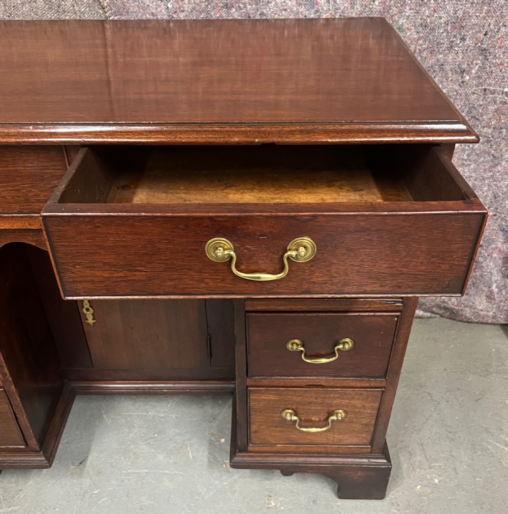 A George III mahogany kneehole desk featuring multiple drawers with brass swan-neck handles, a central recessed cupboard, and bracket feet. View VIII