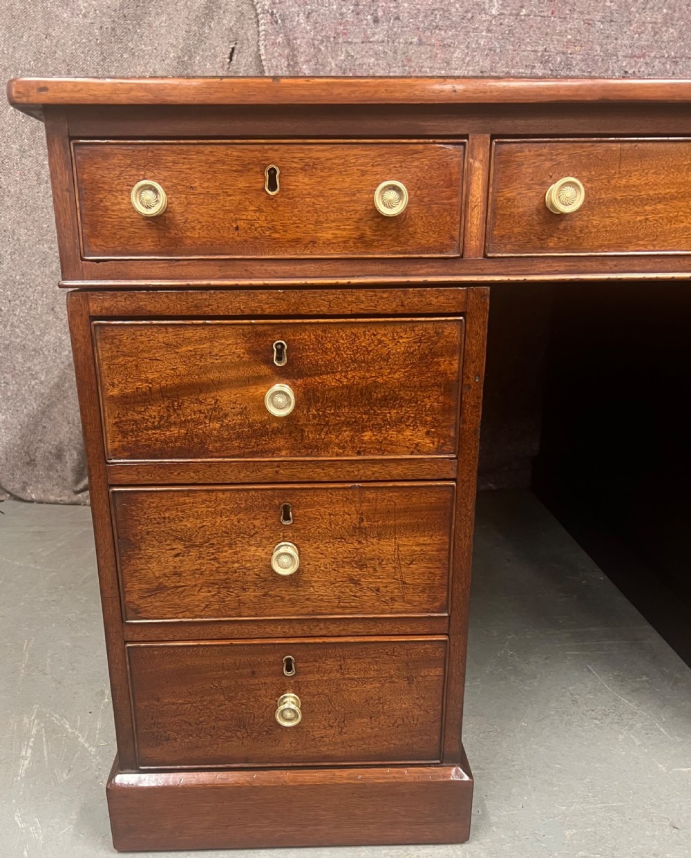 A George III mahogany partners desk featuring a leather writing surface, multiple drawers with turned brass handles, and a twin-pedestal design. View VII