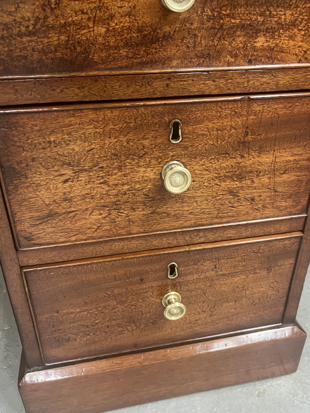 A George III mahogany partners desk featuring a leather writing surface, multiple drawers with turned brass handles, and a twin-pedestal design. View VIII