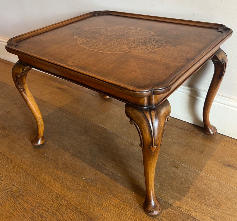 A square walnut Queen Anne style coffee table featuring an inlaid central marquetry medallion, a raised tray rim, and curved cabriole legs ending in pad feet.