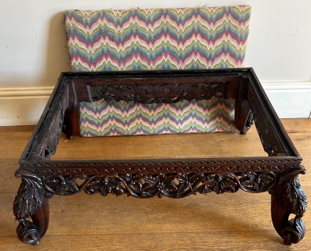 A large rectangular Anglo-Indian stool featuring an intricately carved dark hardwood apron and cabriole legs, topped with a flame-stitch patterned tapestry cushion. View III