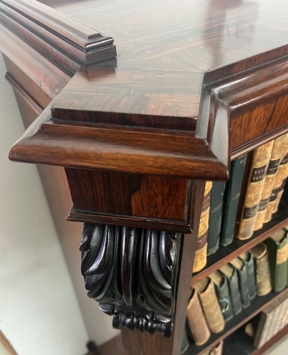An antique dark rosewood open bookcase featuring three wide shelves, rich figured grain, and hand-carved decorative corbels on the upper front corners. View XIII