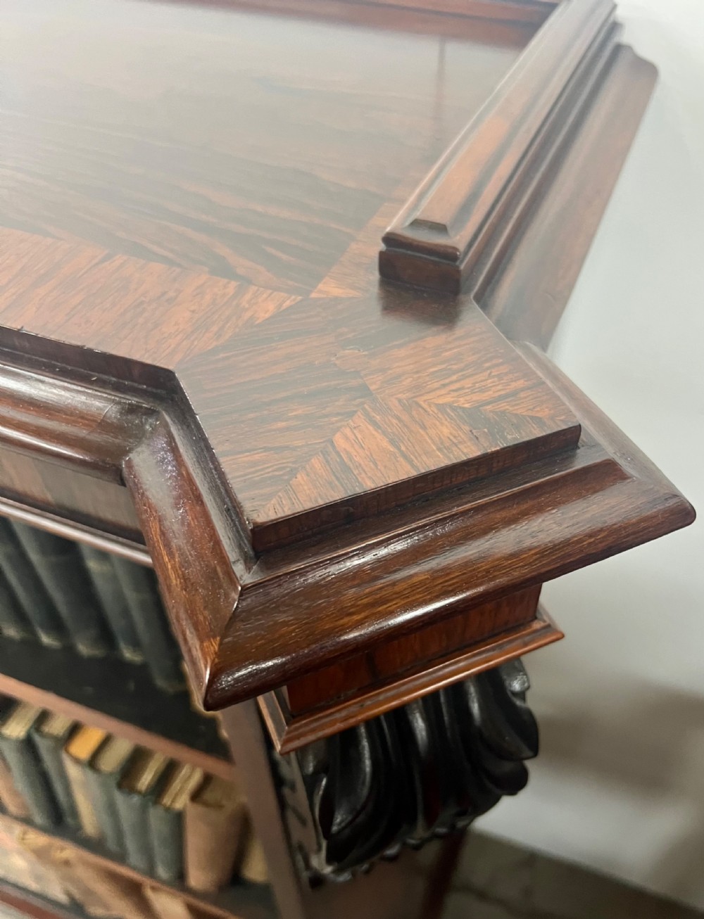 An antique dark rosewood open bookcase featuring three wide shelves, rich figured grain, and hand-carved decorative corbels on the upper front corners. View XV
