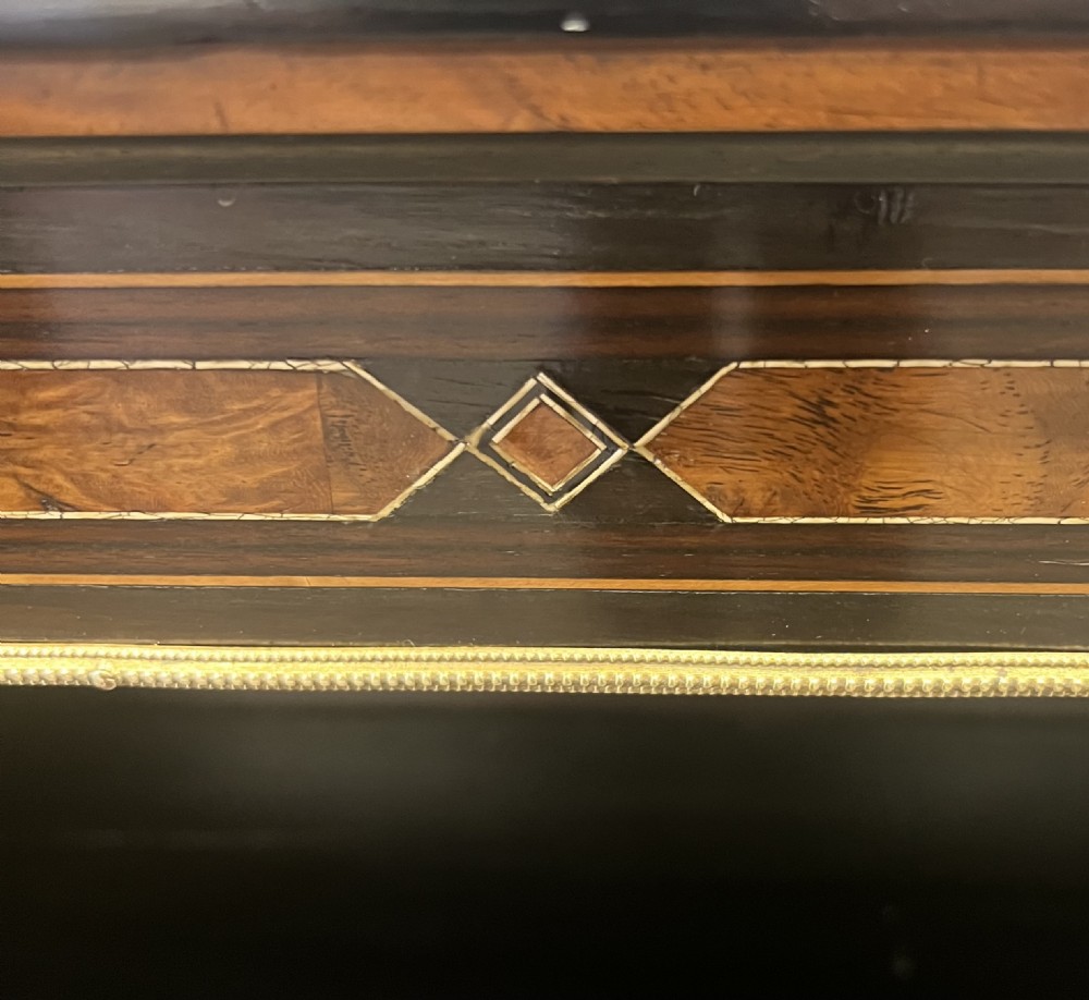 A small ebonised open bookcase with three shelves, featuring burr walnut inlay banding and thin brass moulding detailing. View VII