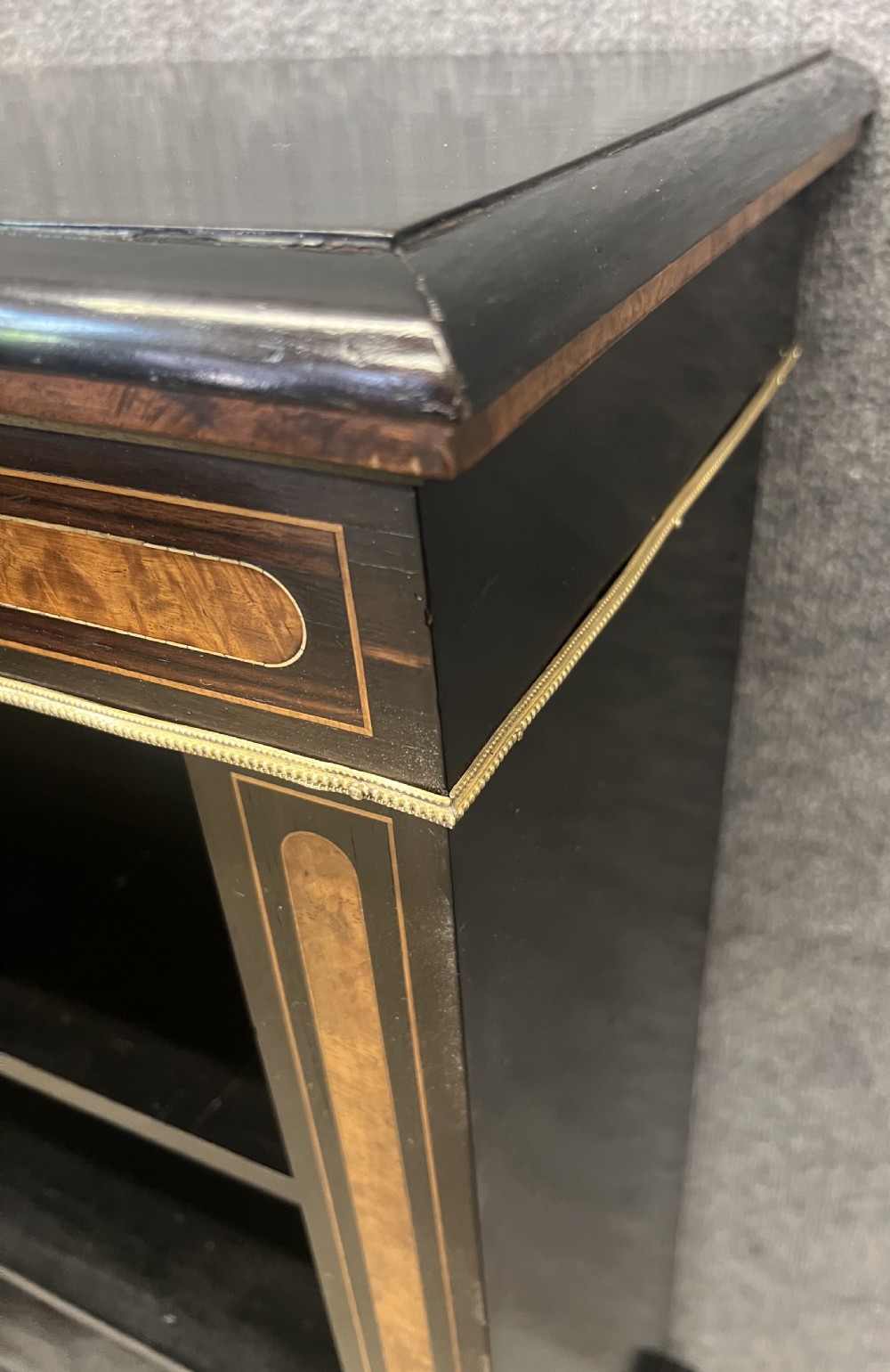 A small ebonised open bookcase with three shelves, featuring burr walnut inlay banding and thin brass moulding detailing. View VIII