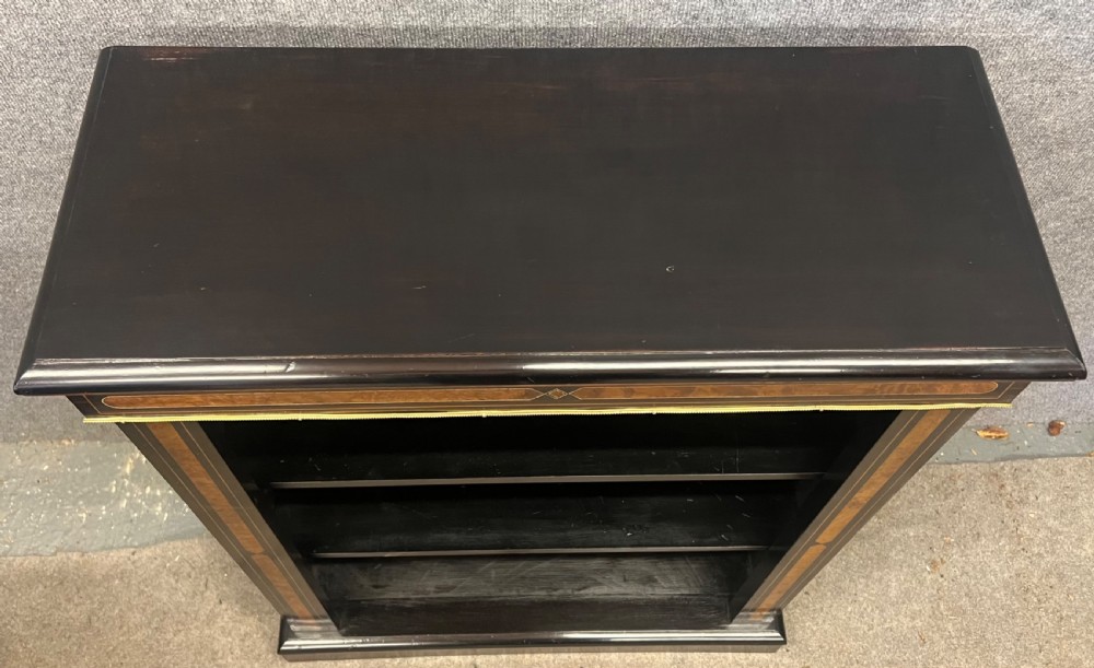 A small ebonised open bookcase with three shelves, featuring burr walnut inlay banding and thin brass moulding detailing. View XI