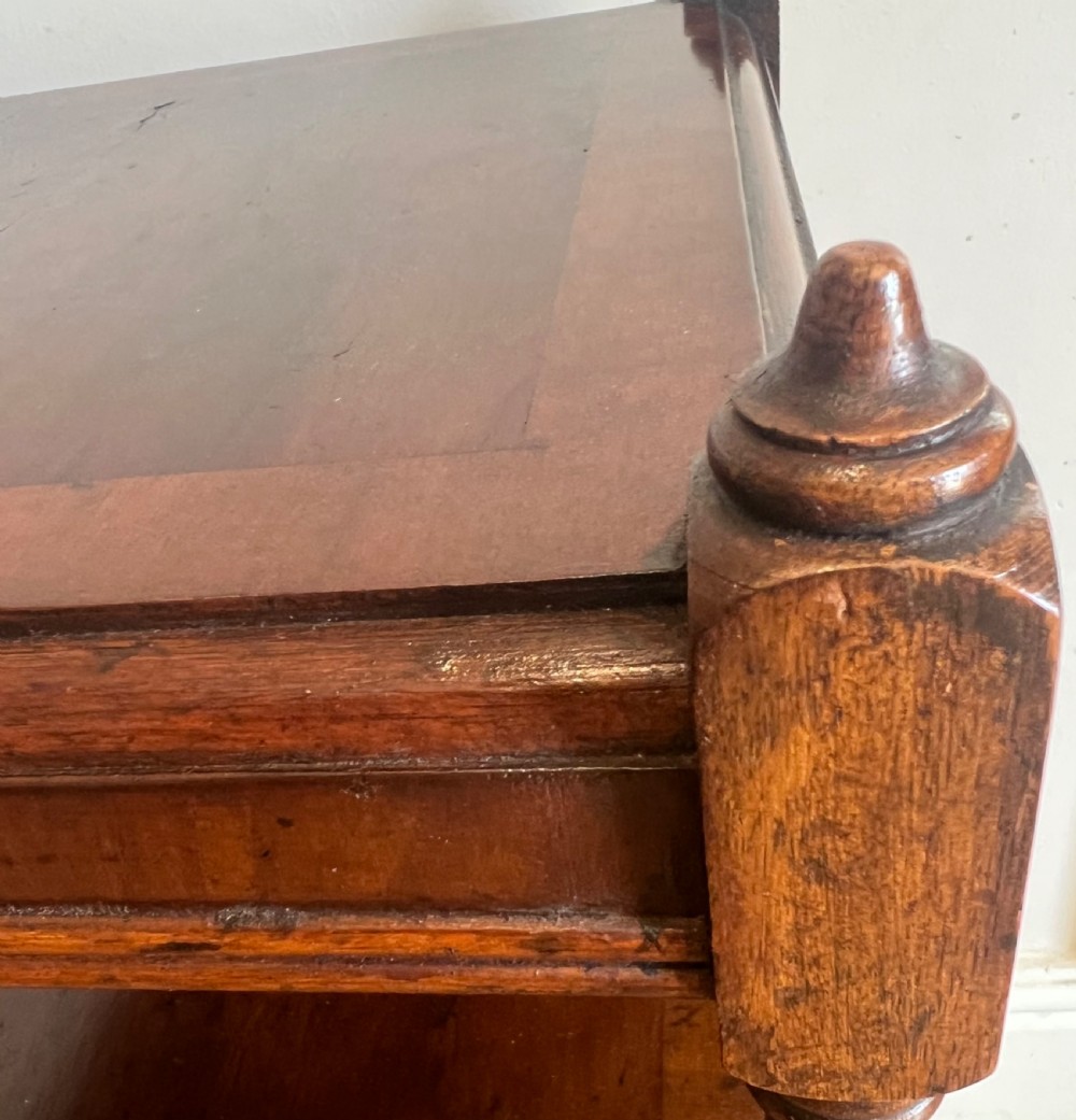 A three-tier dark mahogany antique whatnot featuring turned upright supports, top corner finials, and small brass castors on the legs. View II