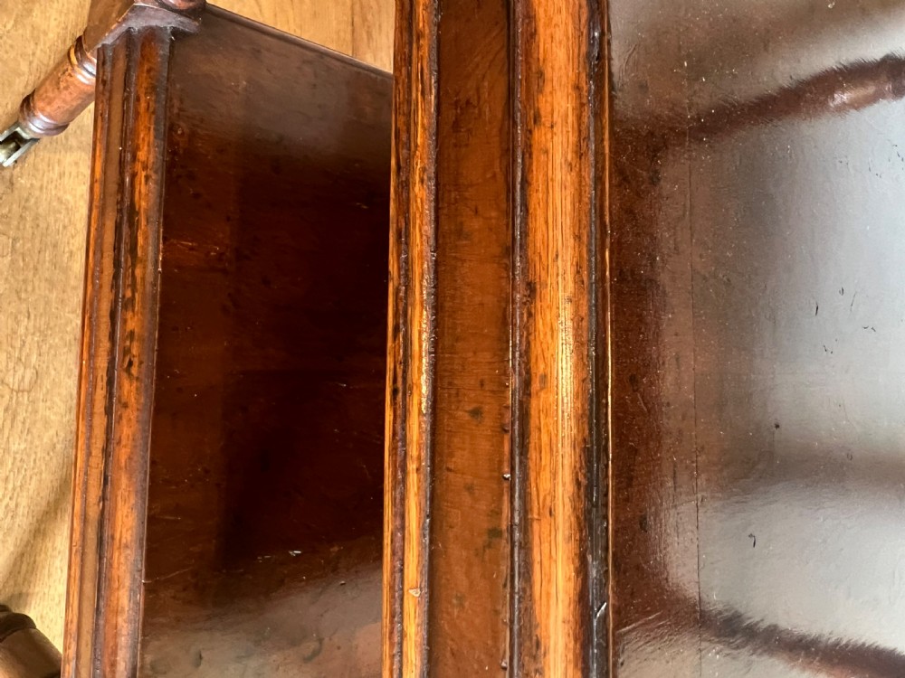 A three-tier dark mahogany antique whatnot featuring turned upright supports, top corner finials, and small brass castors on the legs. View III