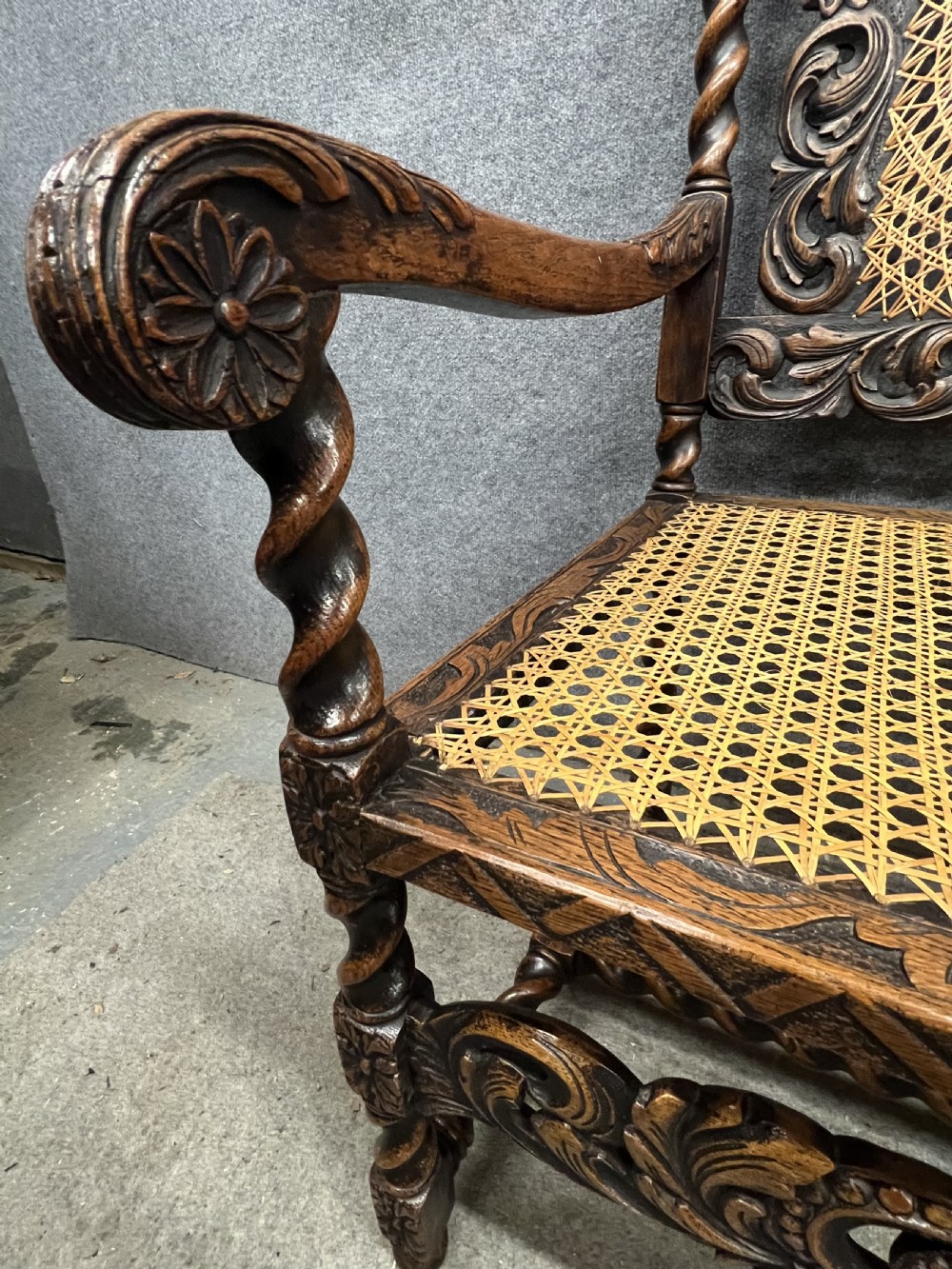 A carved dark wood Carolean style triple chair-back settee with barley twist turnings, crest carving, and woven cane seat and back panels. View VIII