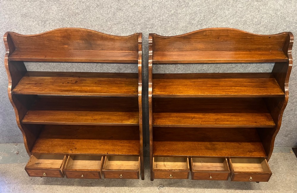 A pair of rich brown mahogany open waterfall bookcases featuring graduated shelves, serpentine side profiles, and three small drawers along the base. View IV