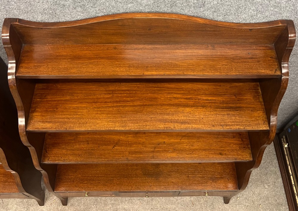 A pair of rich brown mahogany open waterfall bookcases featuring graduated shelves, serpentine side profiles, and three small drawers along the base. View V