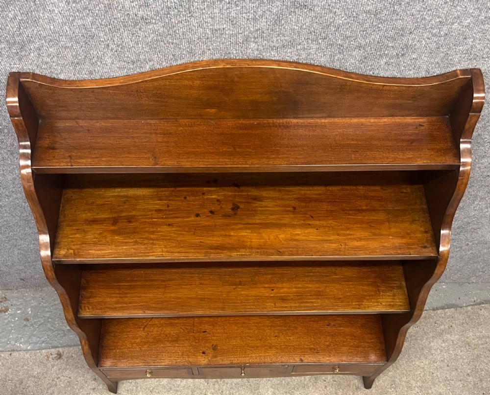 A pair of rich brown mahogany open waterfall bookcases featuring graduated shelves, serpentine side profiles, and three small drawers along the base. View VI
