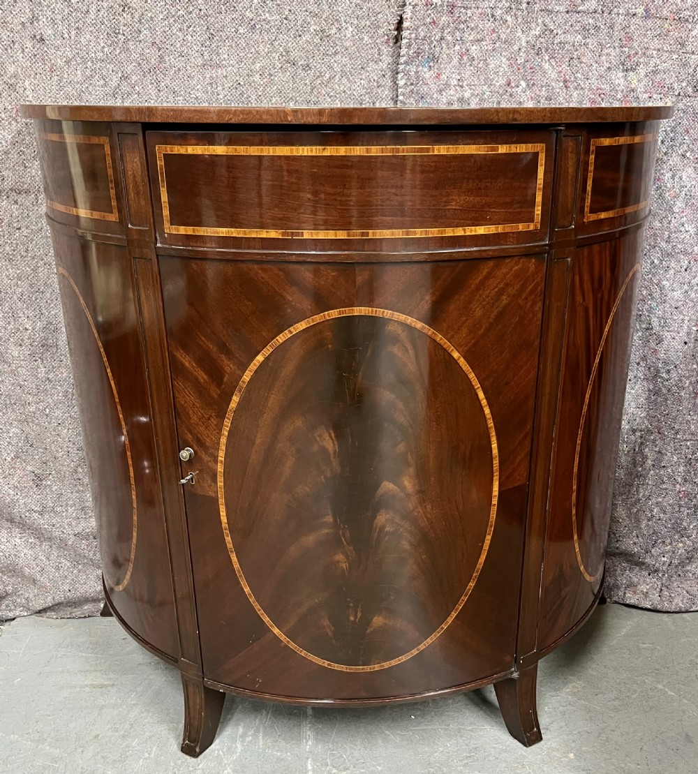 A semi-circular Sheraton Revival mahogany cabinet featuring decorative oval wood inlays, stringing details, and square tapered legs. View II