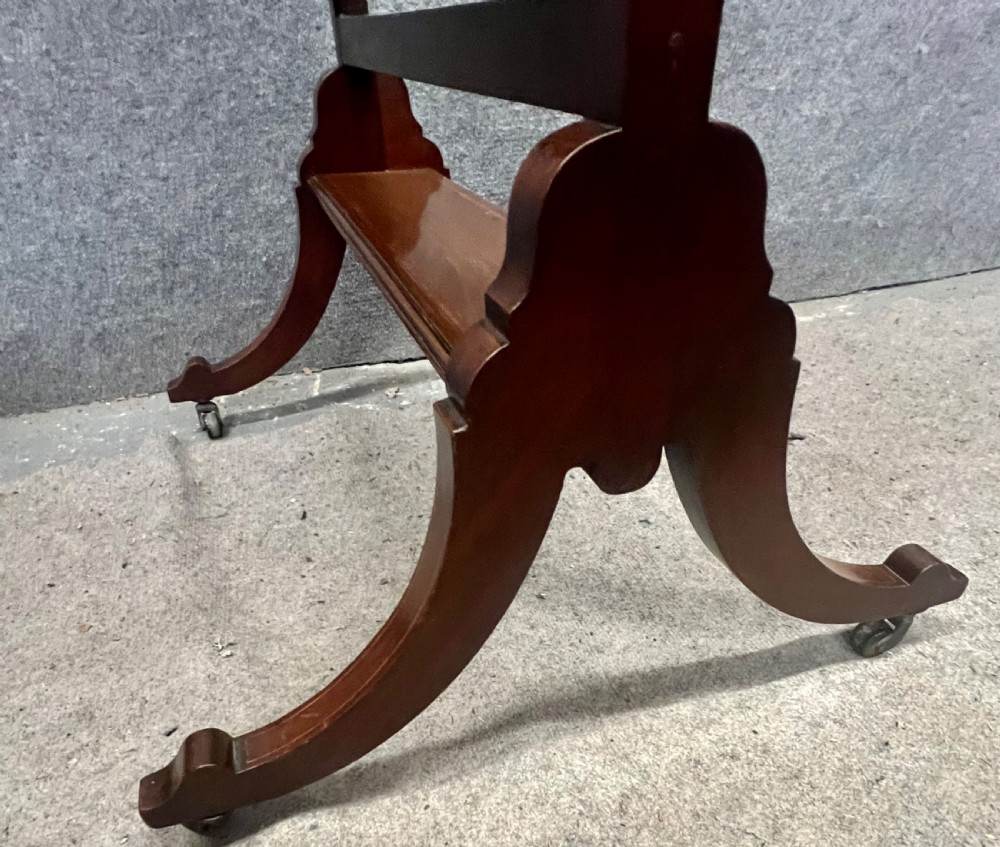 An Edwardian mahogany cheval mirror featuring an arched cresting rail with satinwood line inlay, turned brass finials, bevelled glass plate, and splayed legs on castors. View XII