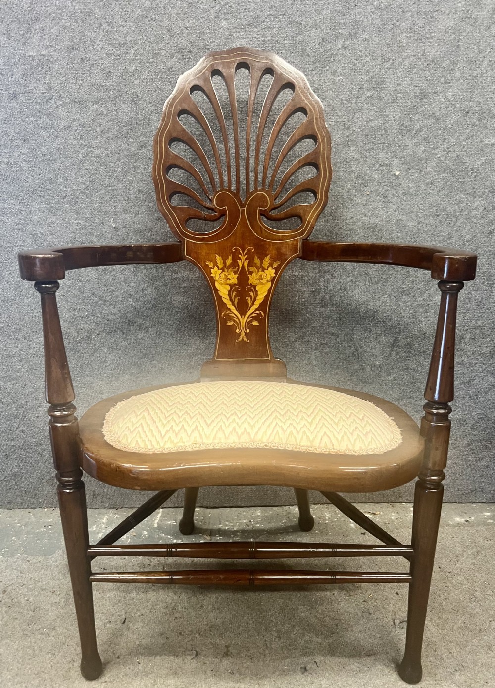 An Art Nouveau mahogany armchair featuring a carved pierced shell backrest, floral marquetry inlay, shaped armrests, and an upholstered seat pad. View X