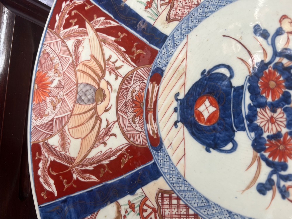 A large circular Japanese Imari porcelain charger featuring radial panelled decoration in cobalt blue, iron red, and white with a central painted flower vase. View IV
