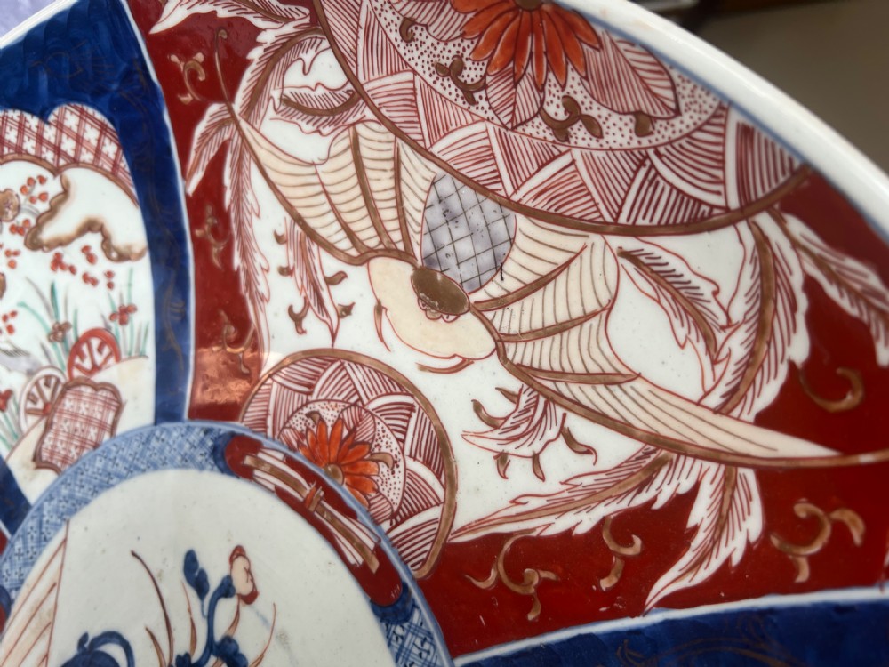 A large circular Japanese Imari porcelain charger featuring radial panelled decoration in cobalt blue, iron red, and white with a central painted flower vase. View VIII
