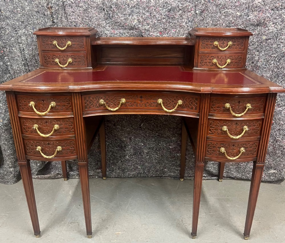 A mahogany writing desk featuring a red leather inset surface, carved drawer fronts, brass swanneck handles, and an elevated superstructure with twin drawer units. View II
