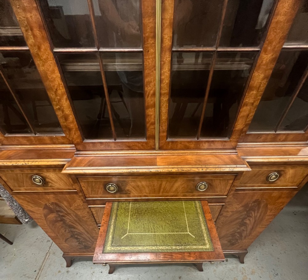 A small Georgian style mahogany breakfront bookcase with upper astragal glazed doors, lower drawers, and oval inlaid cupboard doors. View III