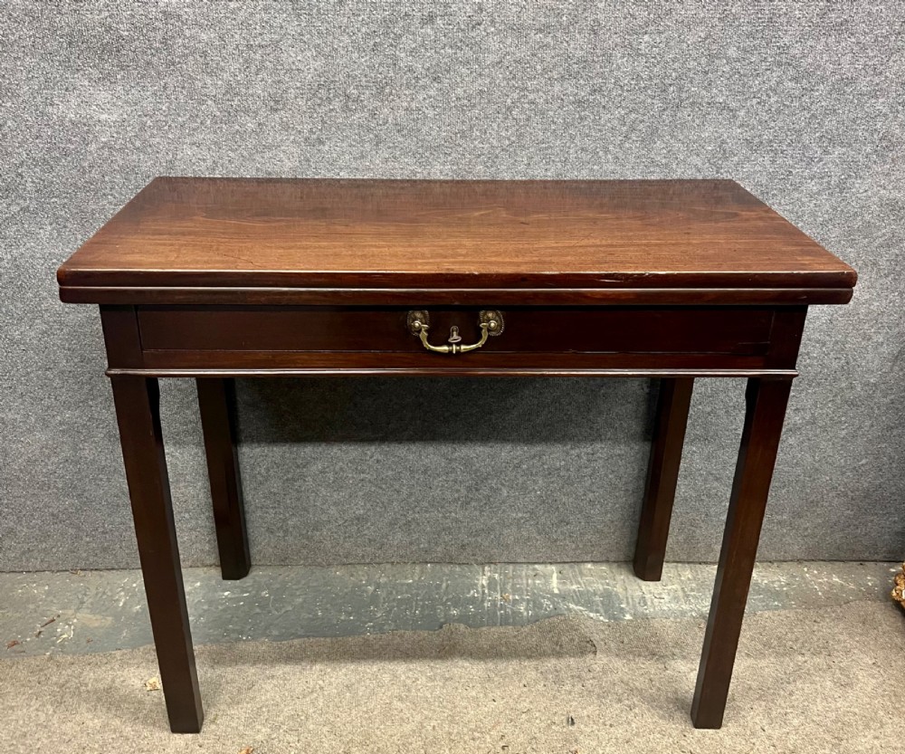 A Georgian dark mahogany fold-over table with straight square legs and a central brass swan-neck handle.